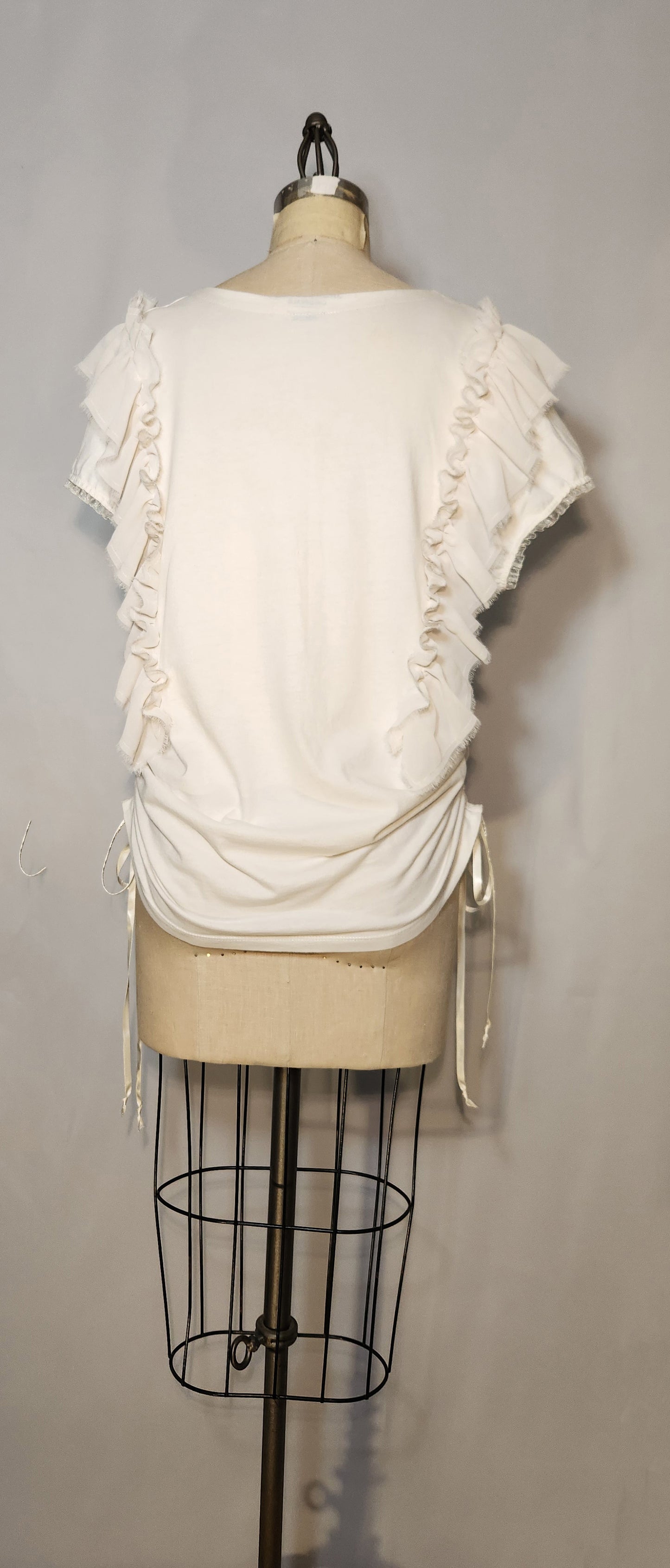 White ruffled top on a mannequin against a gray background