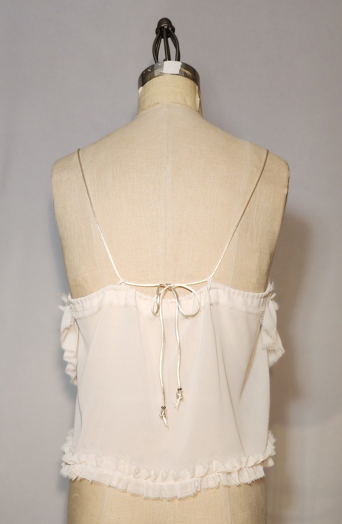 White lace top on a mannequin against a gray background