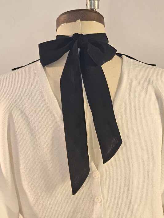 White jabot back neck tie, black on a mannequin against a neutral background