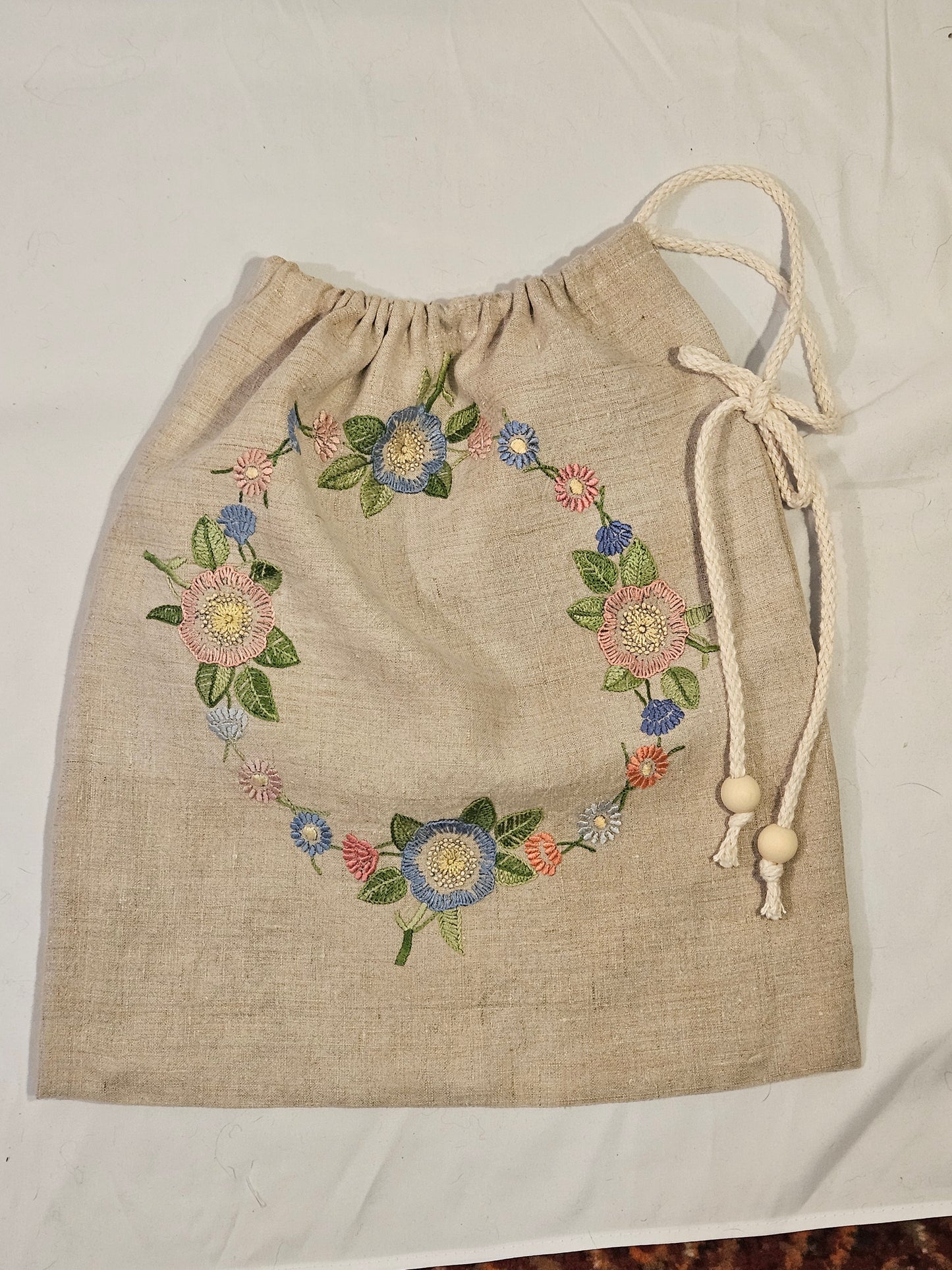 Embroidered floral design on a beige fabric bag with a white background