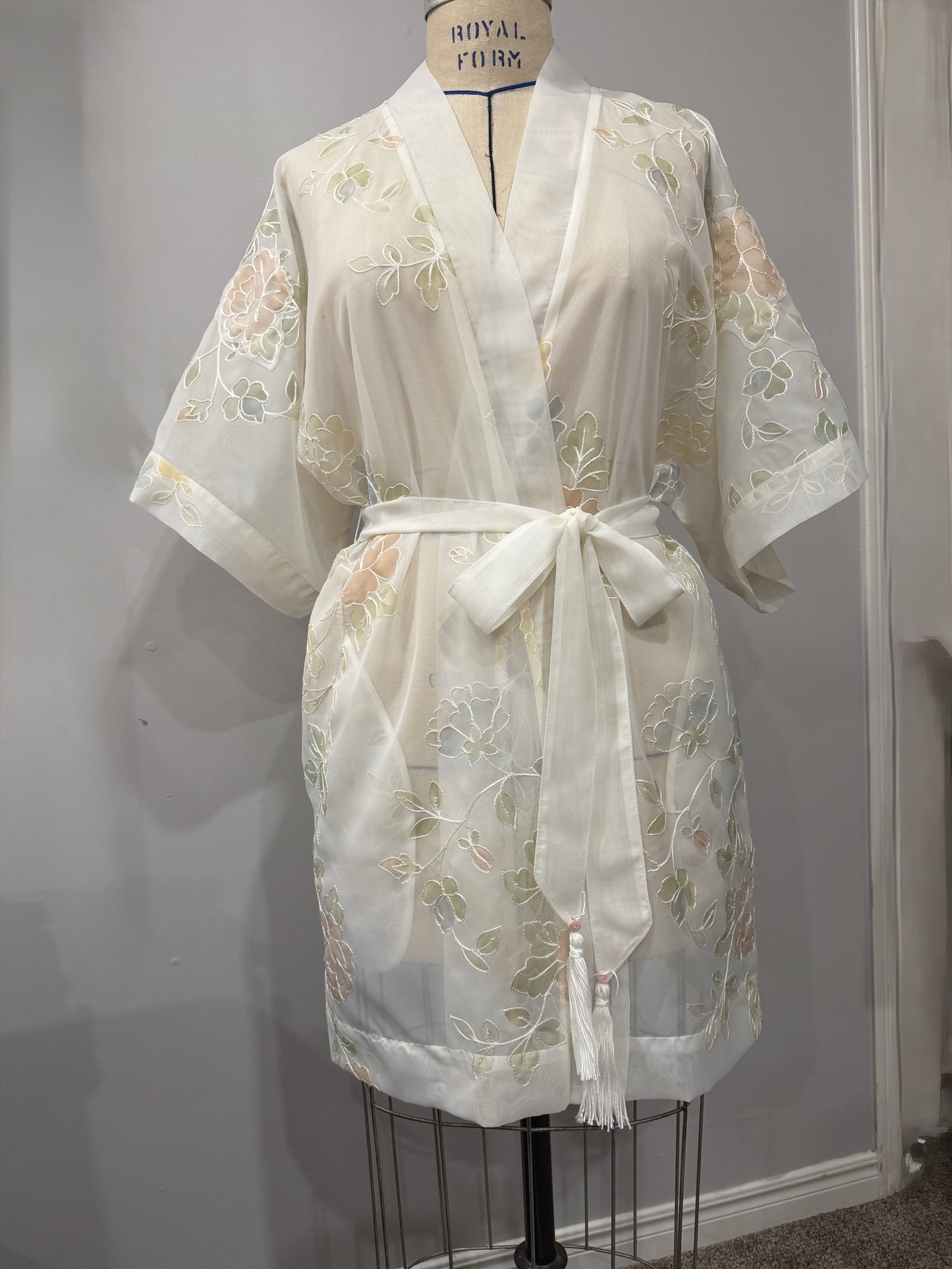 White lace robe on a mannequin against a plain background