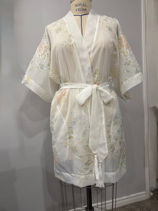 White lace robe on a mannequin against a plain background