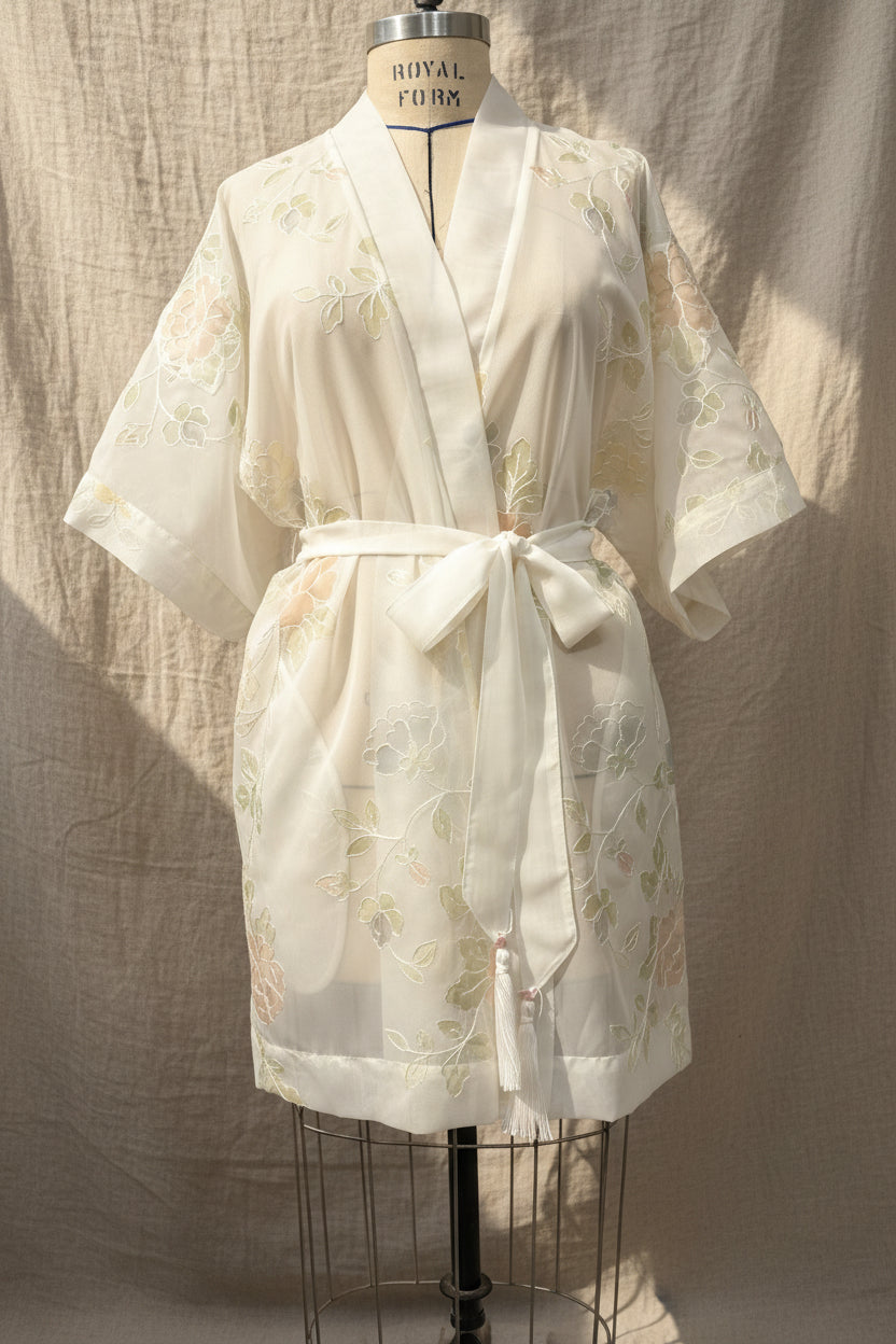 White lace robe on a mannequin against a plain background