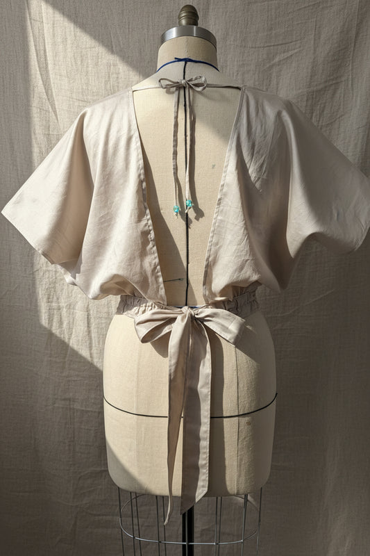 Mannequin wearing a white dress with decorative bows on a plain background