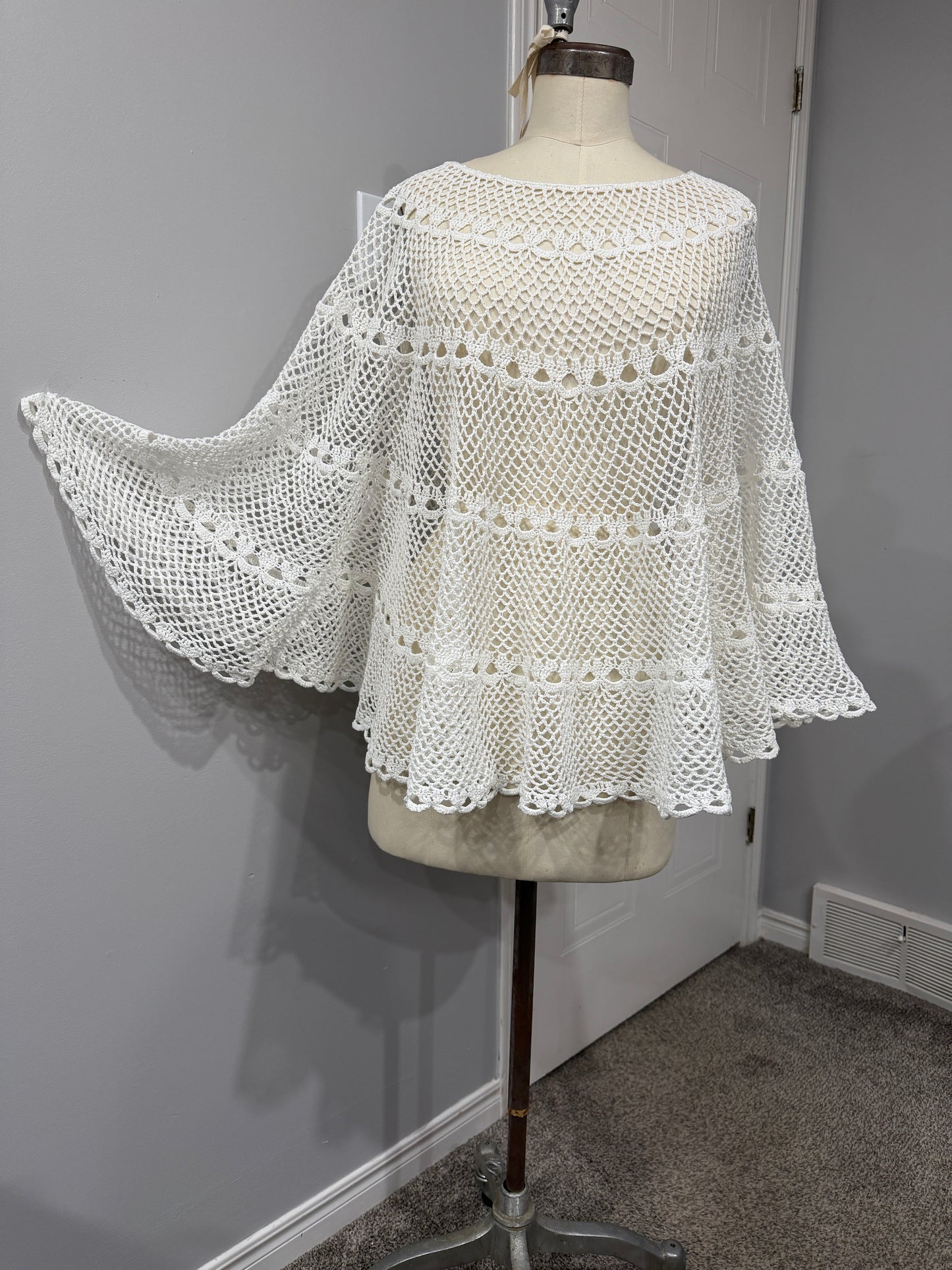 White lace garment on a mannequin against a neutral background