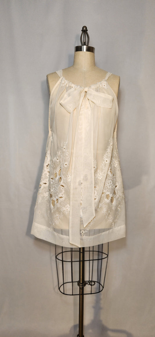 White lace top on a mannequin against a gray background