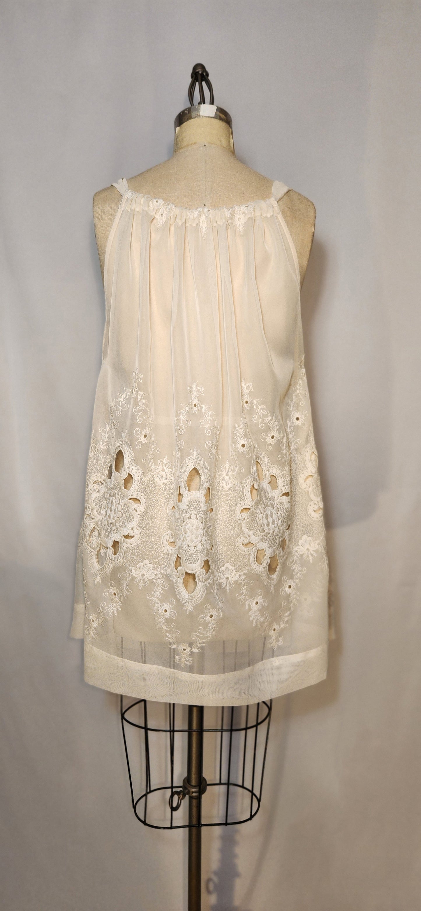 White lace dress on a mannequin against a plain background