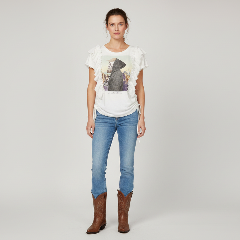 Woman wearing a white t-shirt with a graphic design, blue jeans, and brown boots on a plain background
