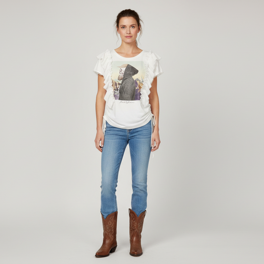 Woman wearing a white t-shirt with a graphic design, blue jeans, and brown boots on a plain background
