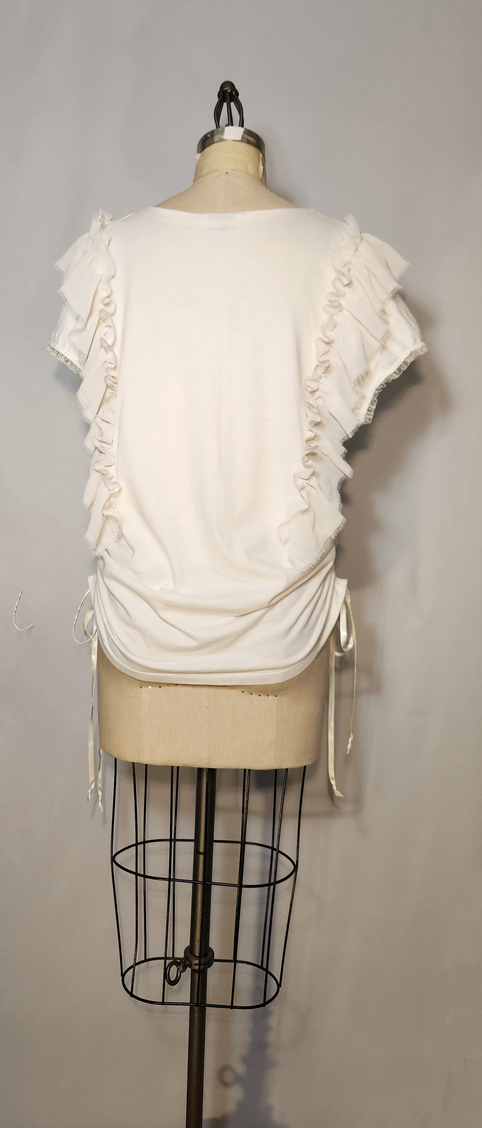 White ruffled top on a mannequin against a gray background