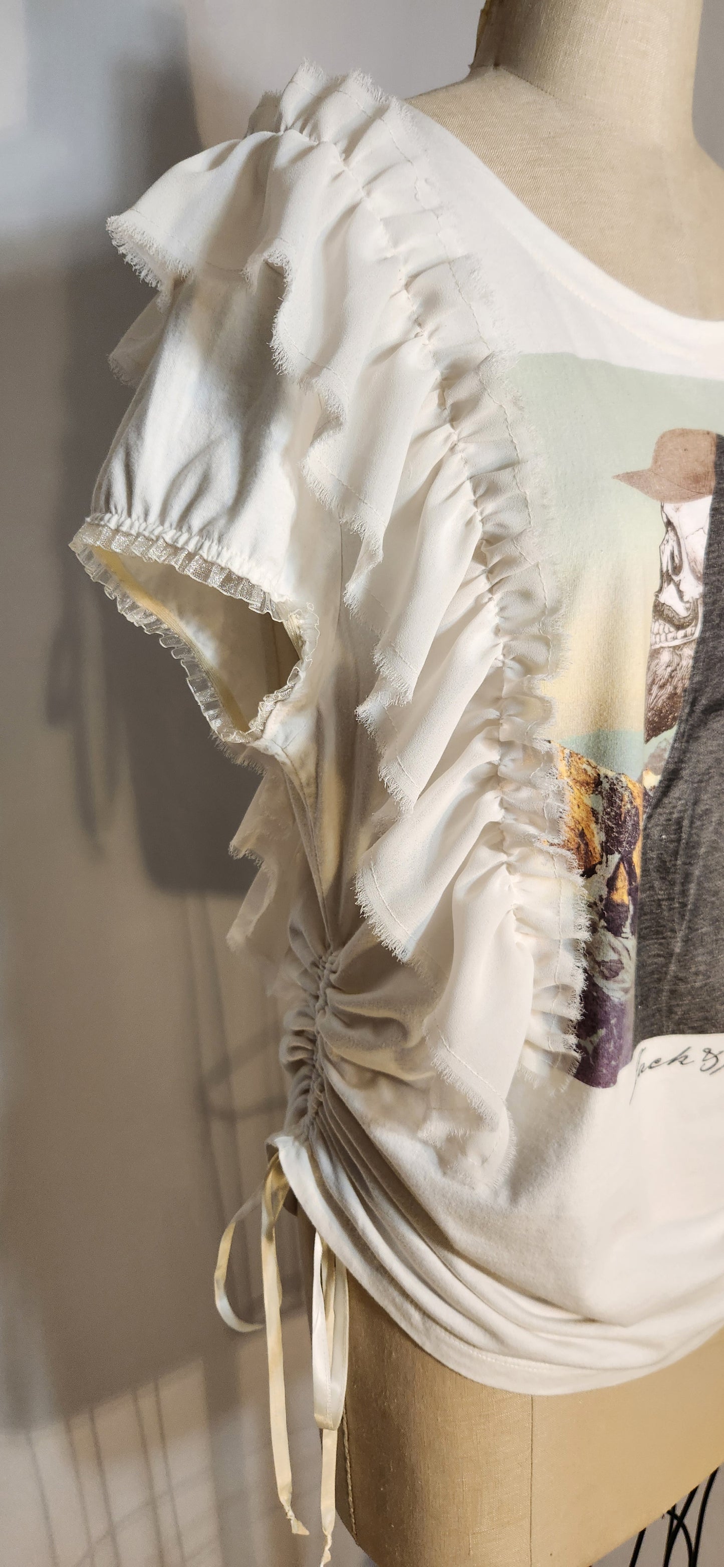 Mannequin wearing a white blouse with ruffled details on a neutral background