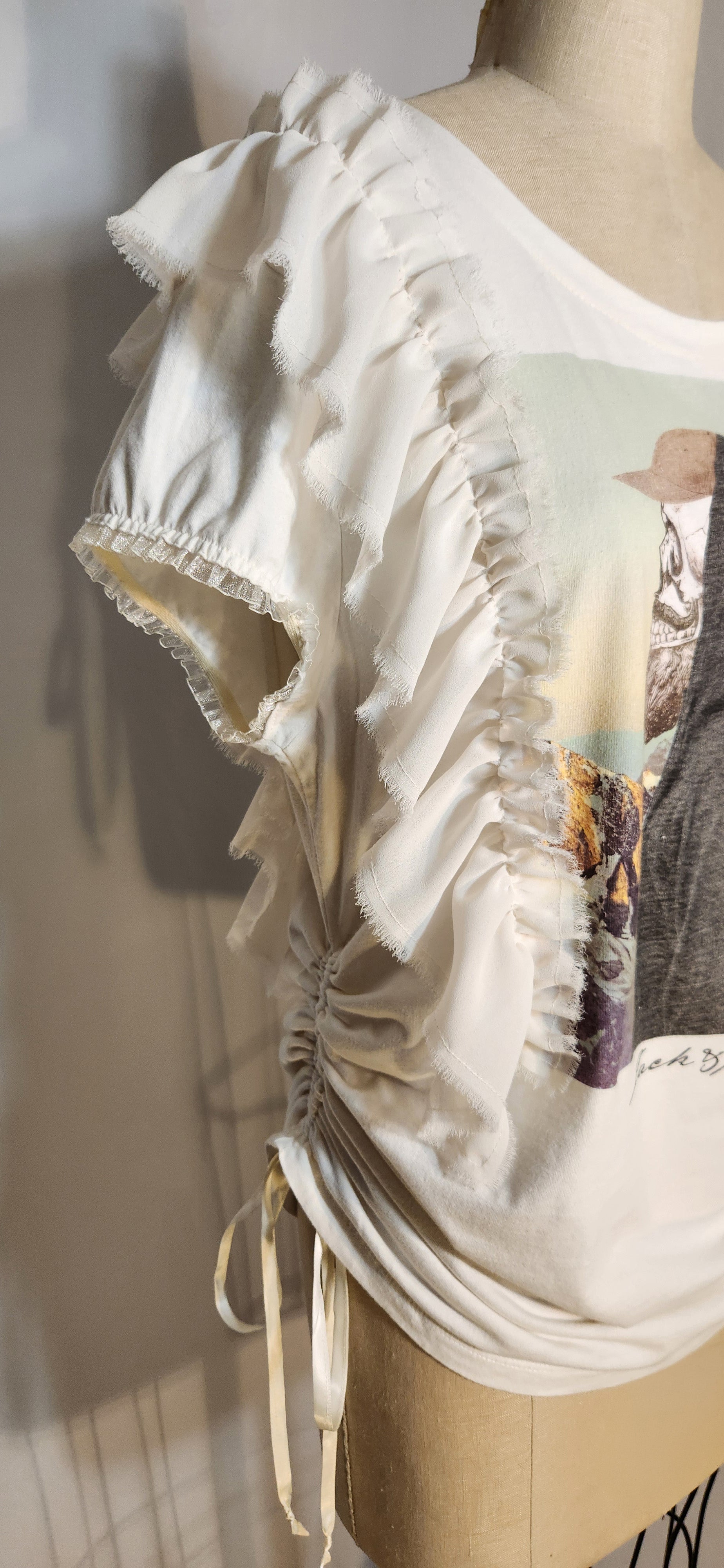 Mannequin wearing a white blouse with ruffled details on a neutral background