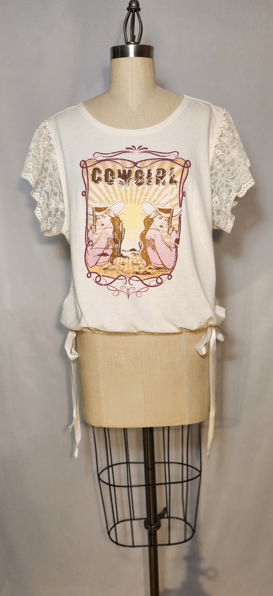 White lace-trimmed top with 'Cowgirl' graphic on a mannequin against a neutral background