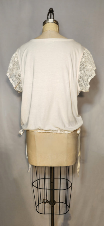White lace-trimmed top on a mannequin against a gray background