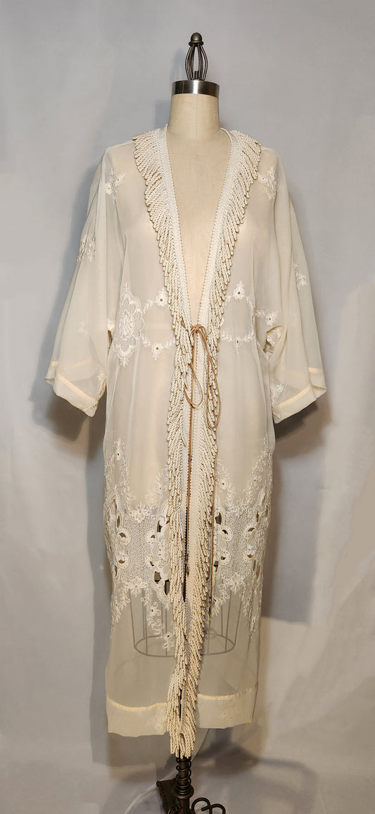 Cream-colored embroidered dress on a mannequin against a gray background