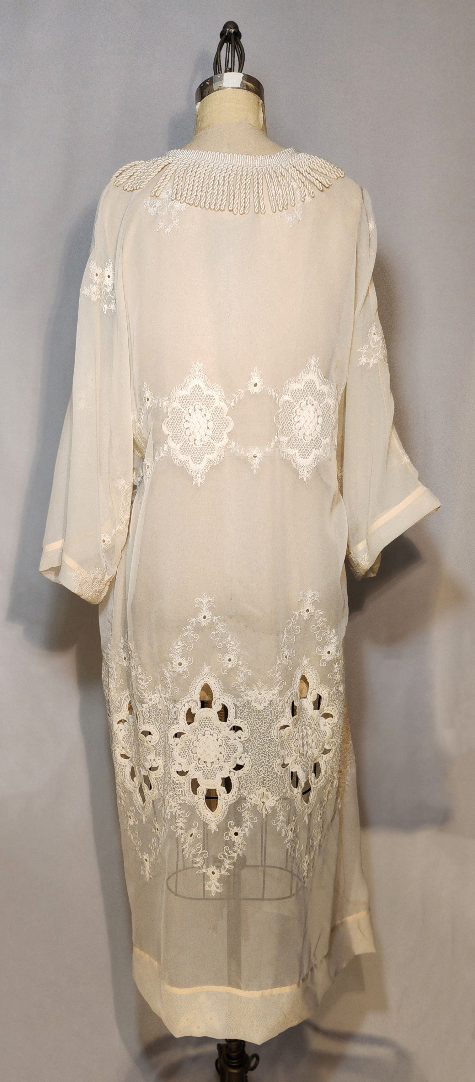 White embroidered dress on a mannequin against a gray background