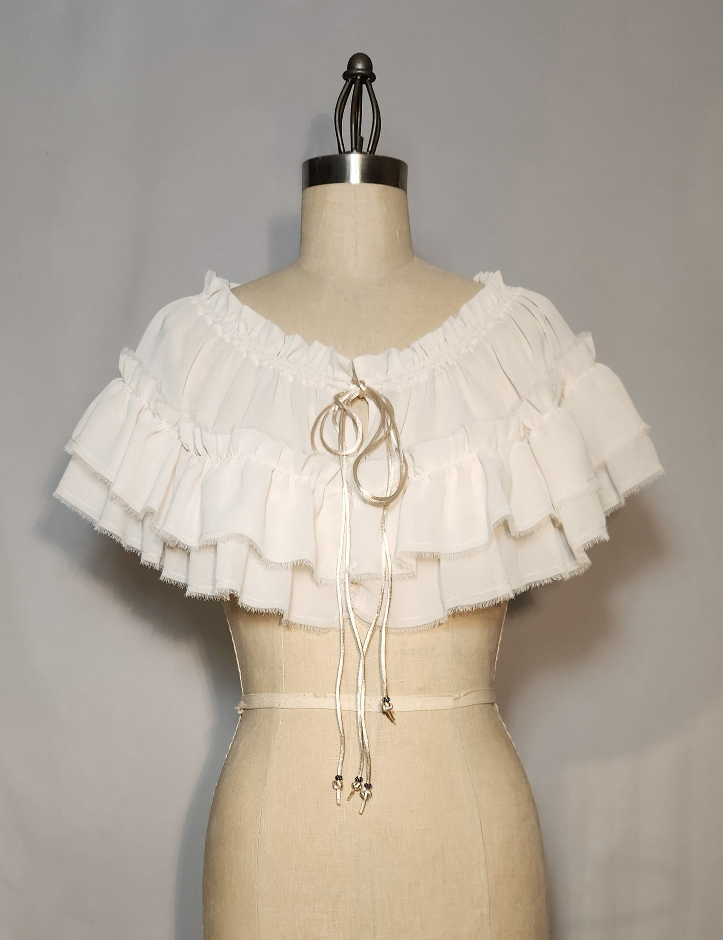 White ruffled top on a mannequin against a plain background
