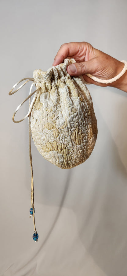Hand holding a textured drawstring bag against a neutral background