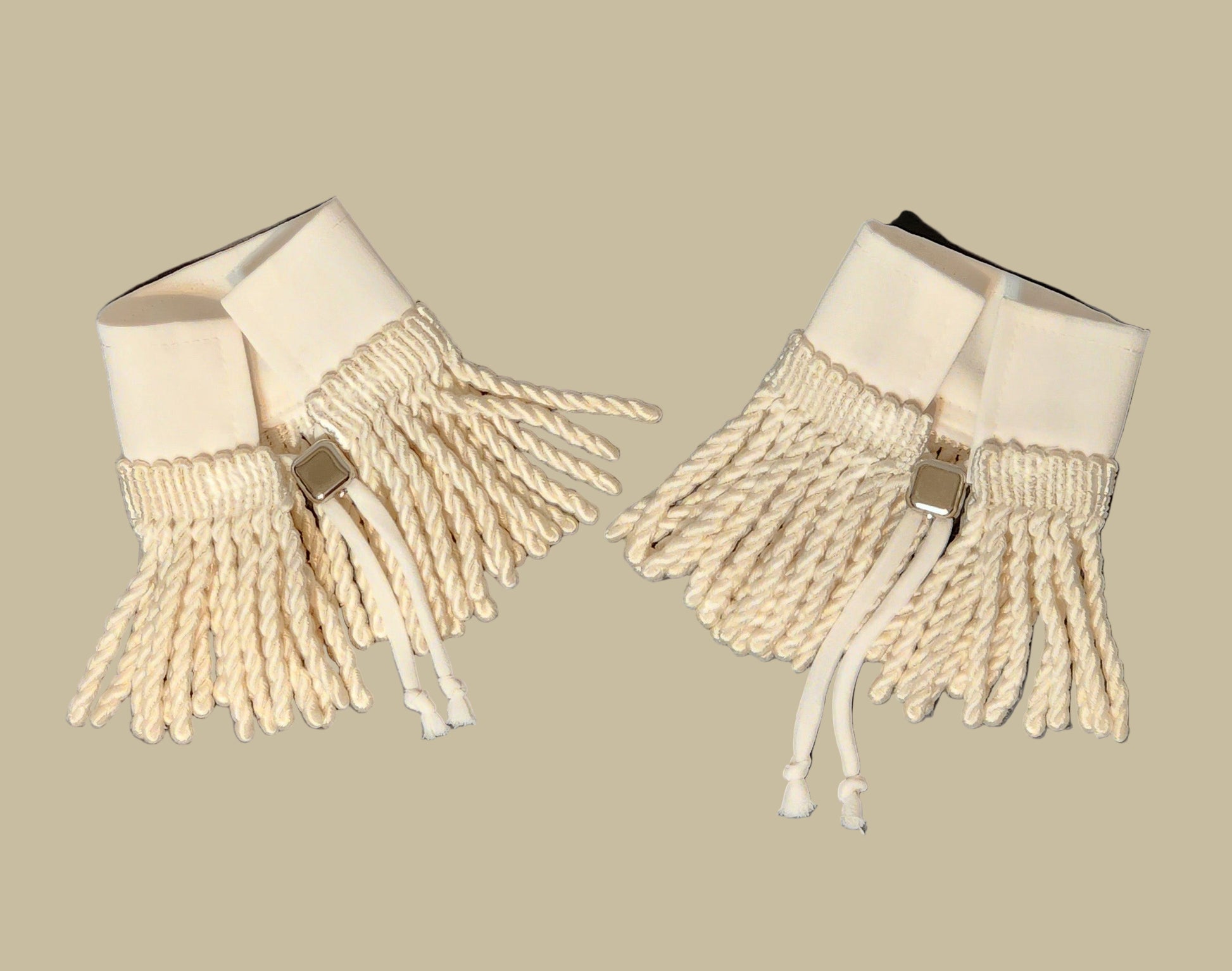 Pair of beige fringed cuffs on a gray background