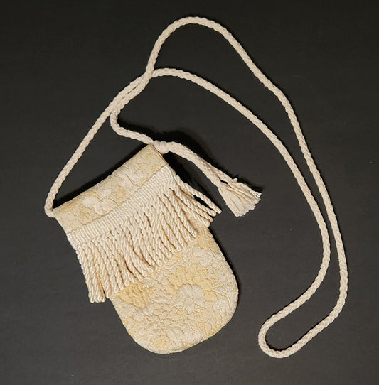 Decorative beige bag with tassels on a dark background