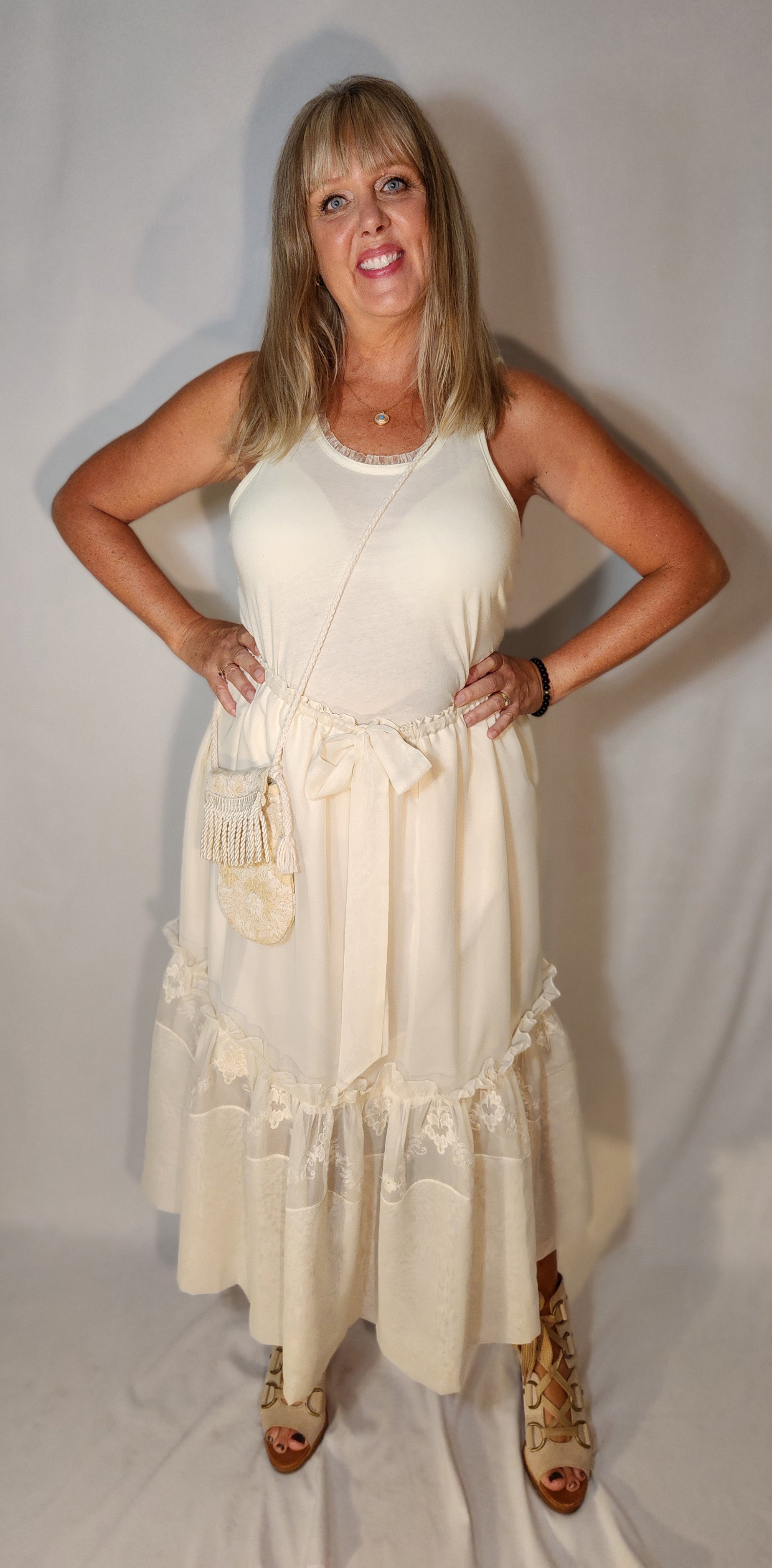Woman wearing a white dress with ruffles against a plain background