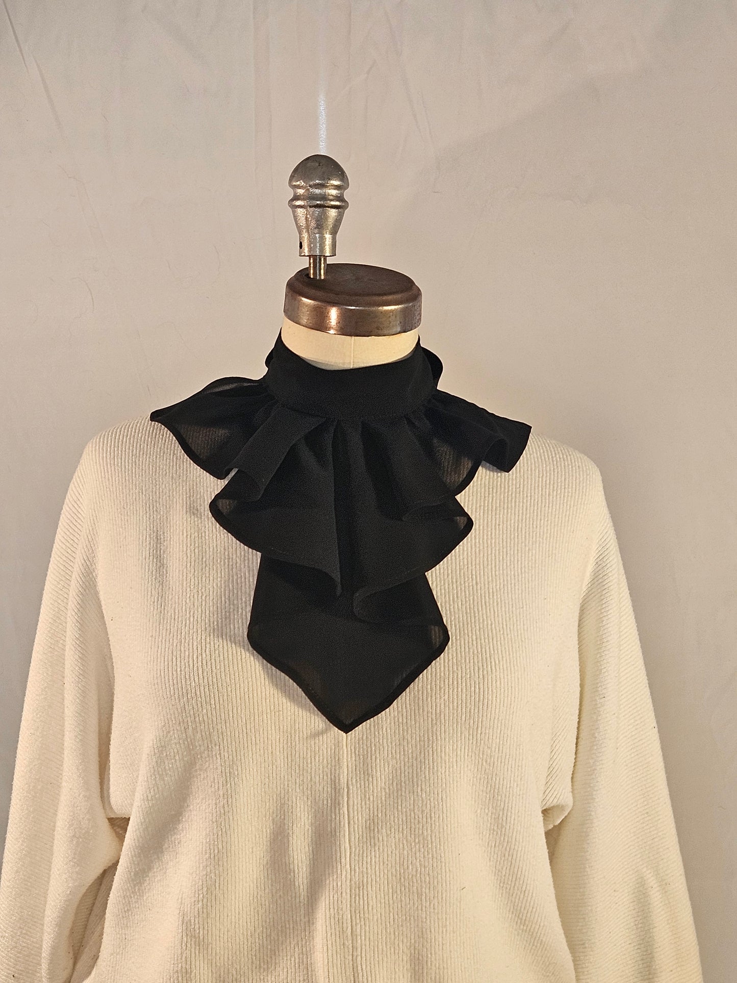 Mannequin with black bow and beige garment on a neutral background