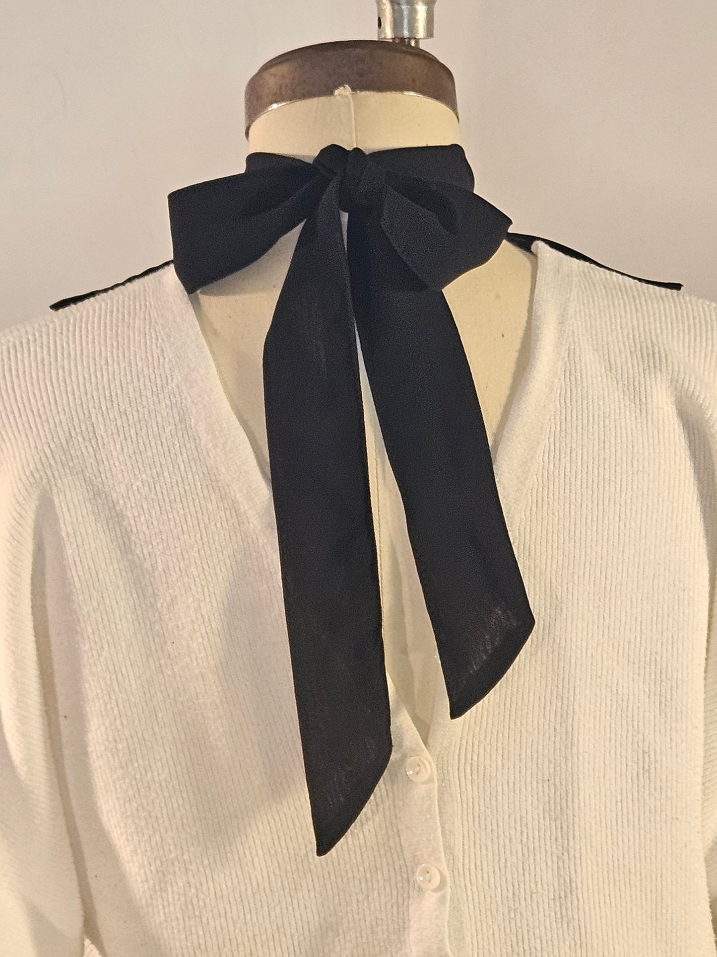 White jabot back neck tie, black on a mannequin against a neutral background