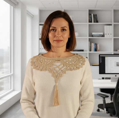 Woman wearing a cream sweater with intricate beaded neckline against a plain background