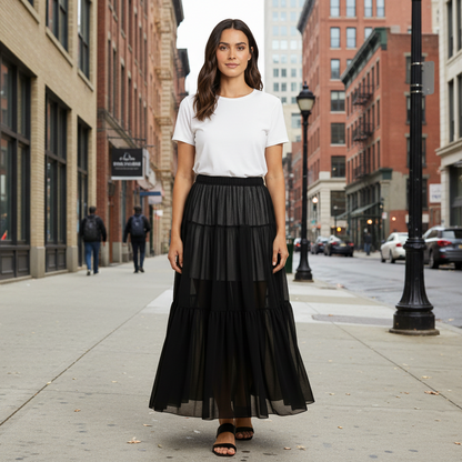 Woman wearing a white t-shirt and black tiered skirt on a beige background