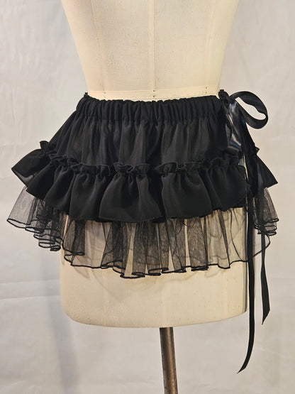 Black ruffled petticoat on a mannequin with a plain background