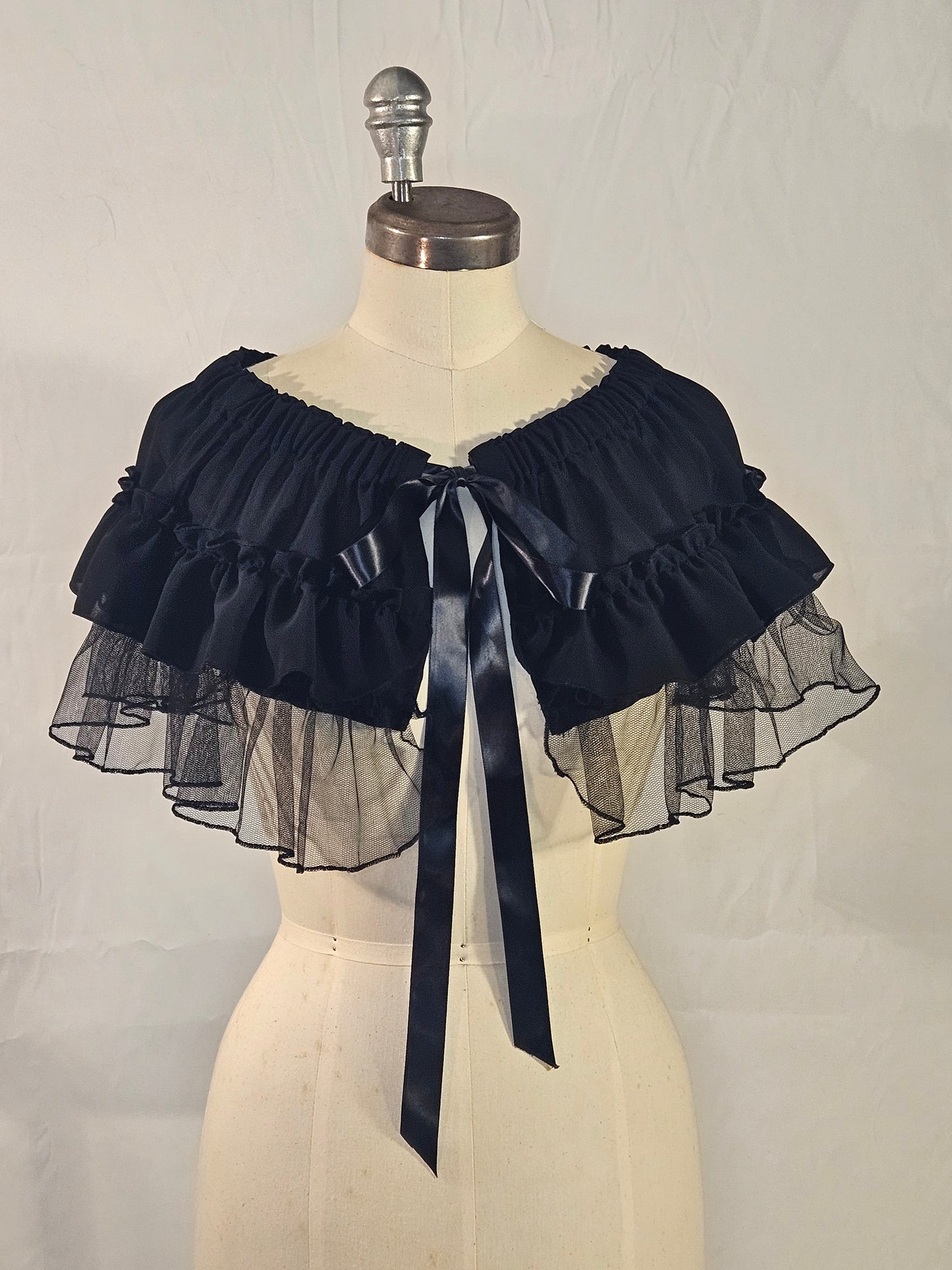 Black cape on a mannequin with a plain background