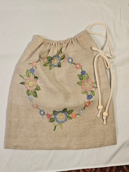 Embroidered floral design on a beige fabric bag with a white background