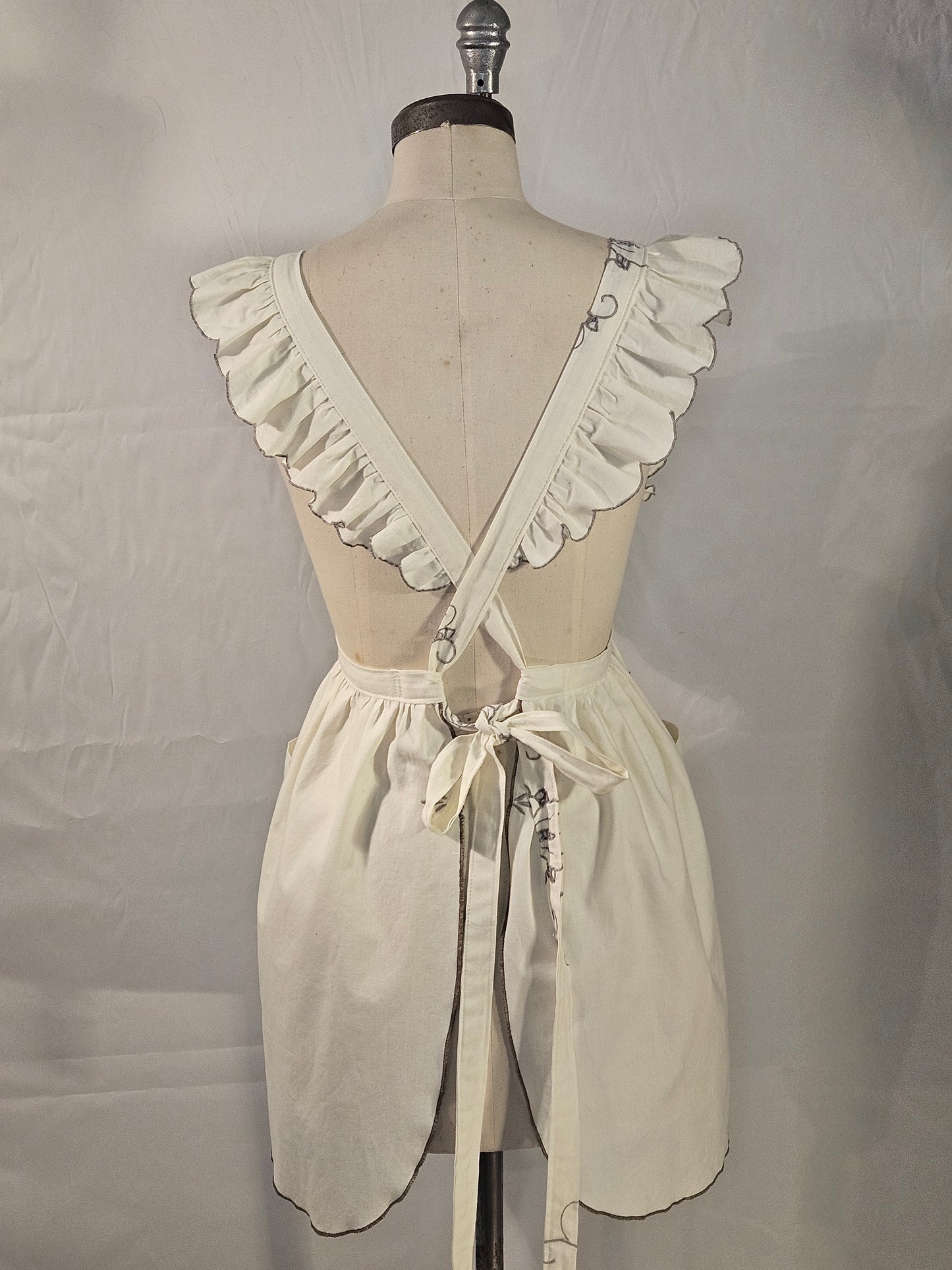 Mannequin wearing a cream-colored dress with ruffled details on a plain background
