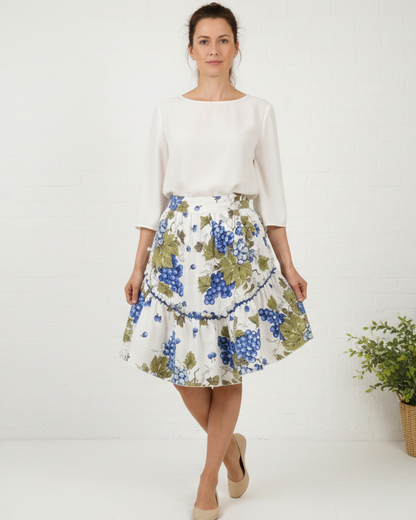 Woman wearing a white blouse and floral skirt on a beige background