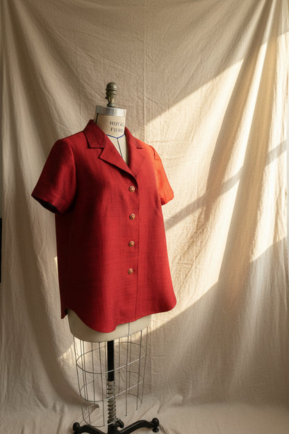 Red short-sleeve jacket on a mannequin against a plain wall.