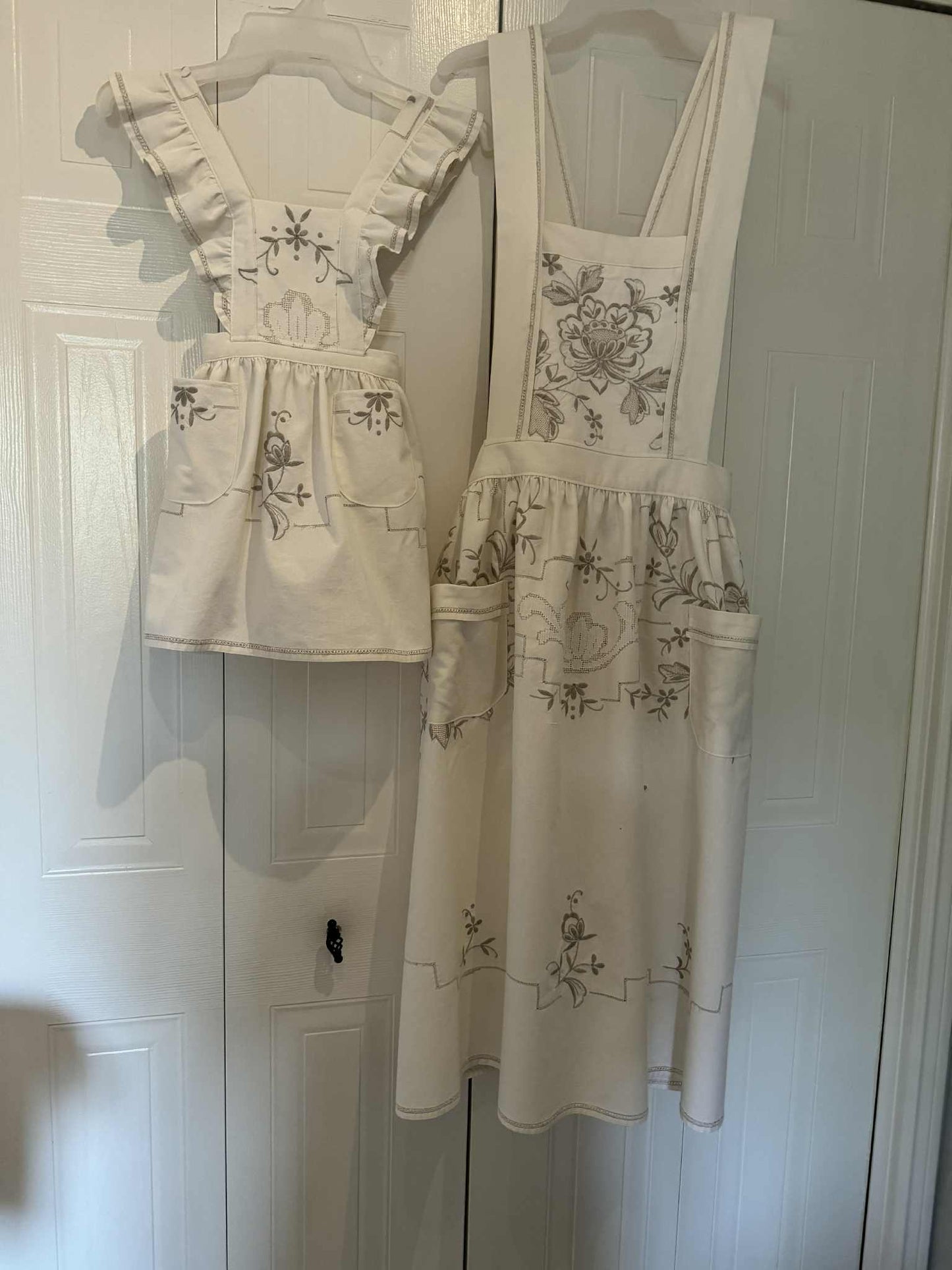 Children and adult matching aprons, white with beige embroidery flowers on a white background 