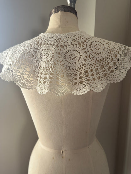 Mannequin wearing a white lace collar against a neutral background