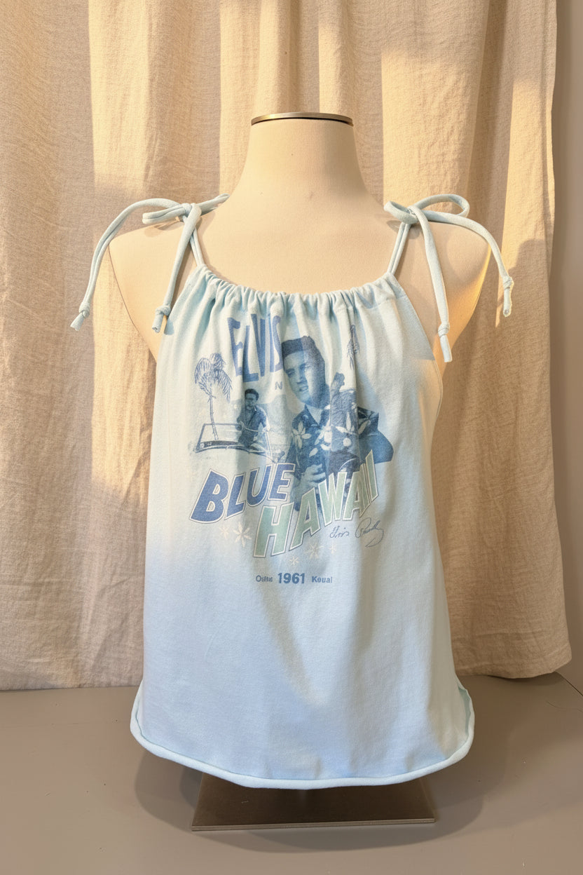 White tank top with blue graphics on a mannequin against a beige curtain background