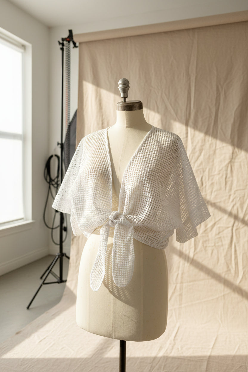 White open-knit short-sleeve wrap top displayed on a cream dress form mannequin in an indoor room setting.