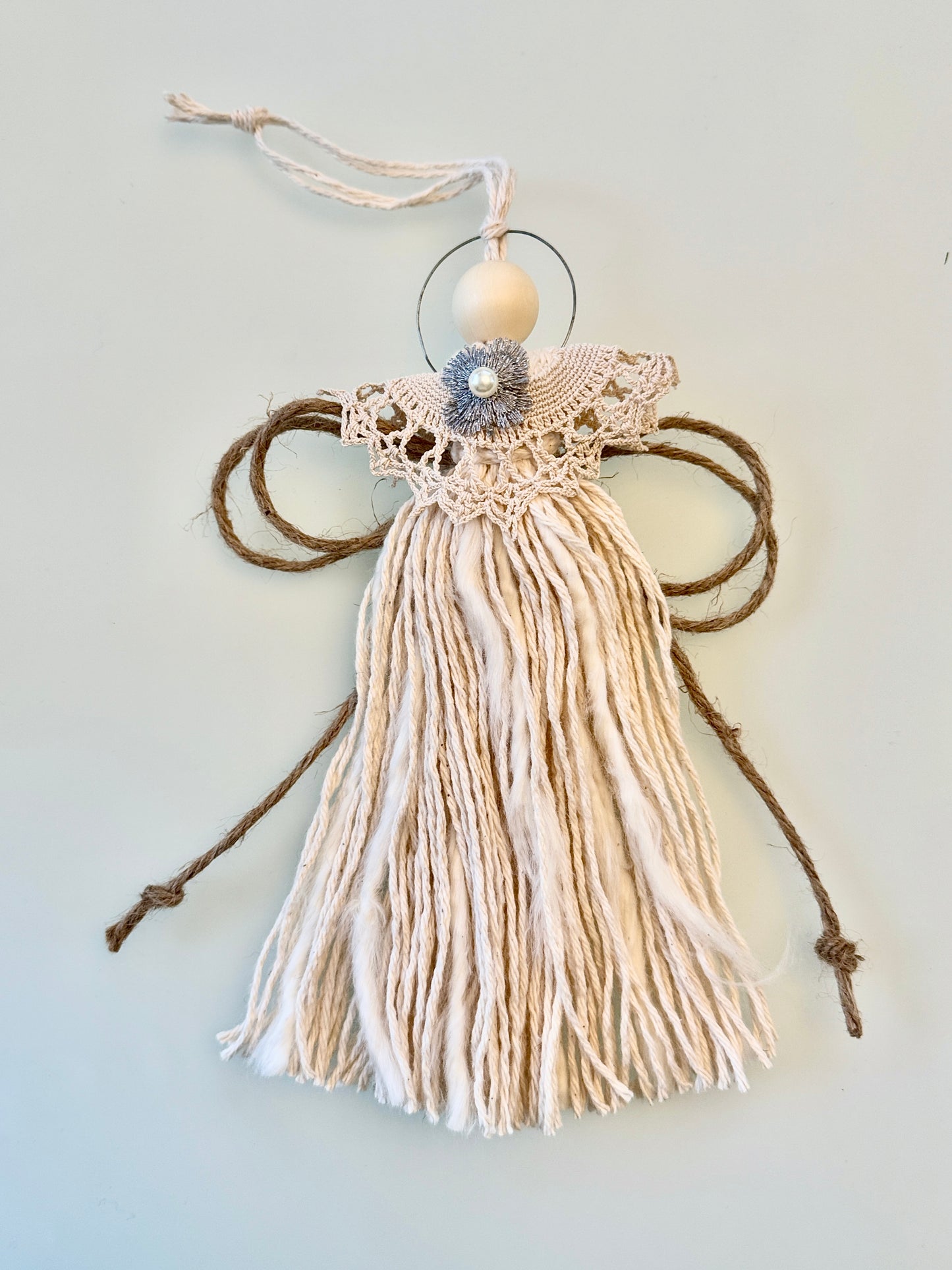 Decorative angel made of yarn and beads on a light gray background