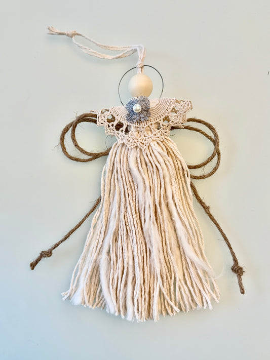 Decorative angel made of yarn and beads on a light gray background