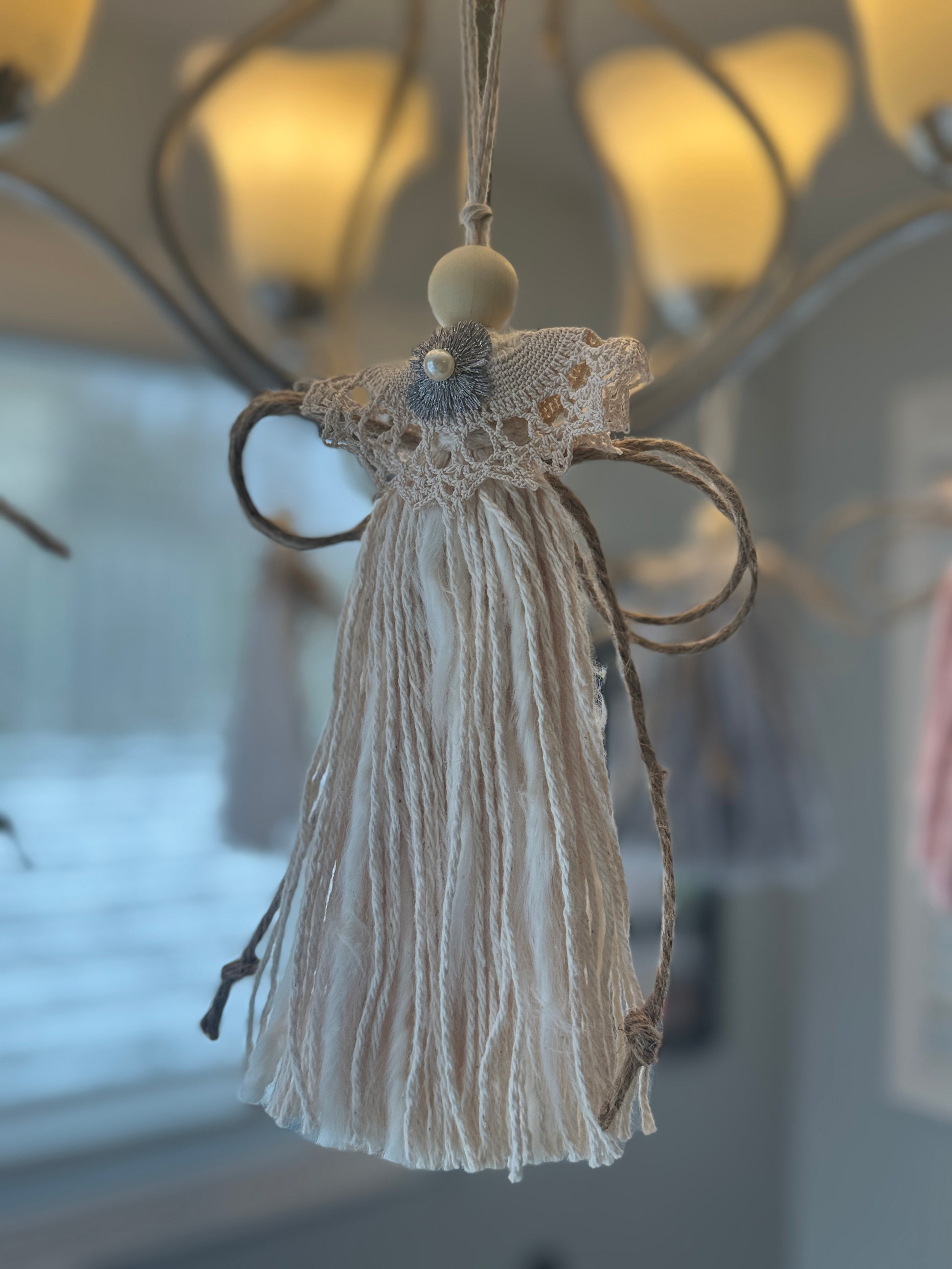 Christmas angel with lace top hanging against a blurred indoor background