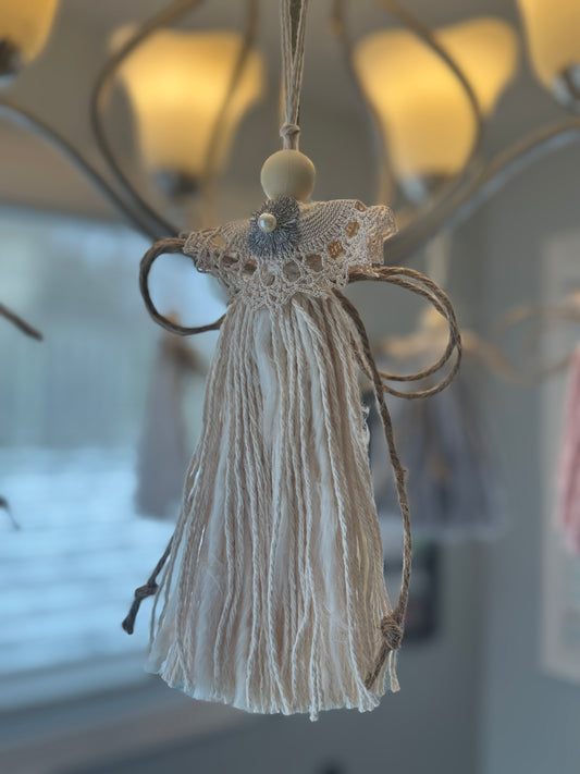 Christmas angel with lace top hanging against a blurred indoor background