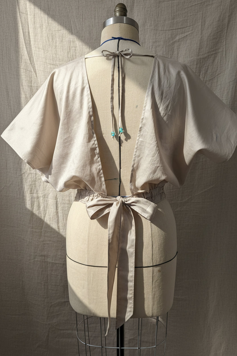 Mannequin wearing a white dress with decorative bows on a plain background