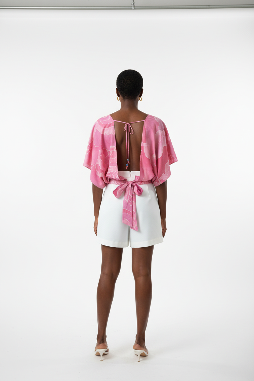 Person wearing a pink open-back top and white shorts on a white background