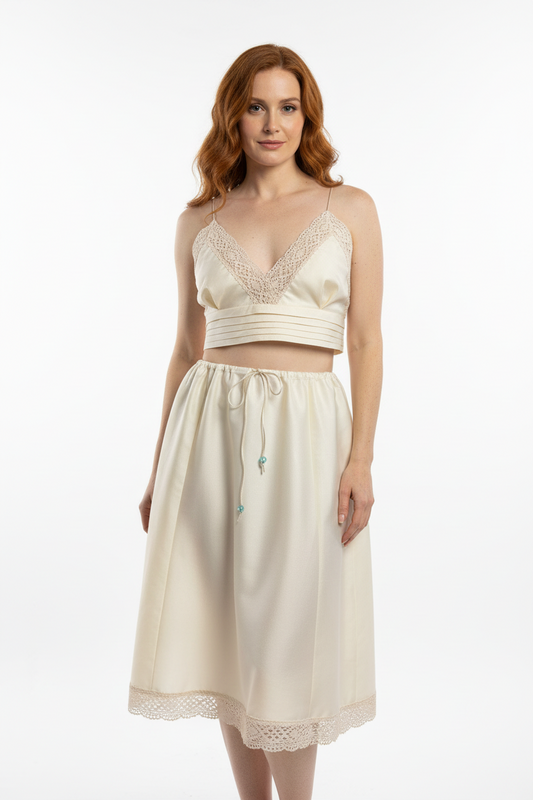 Woman wearing a cream-colored dress with lace details on a white background