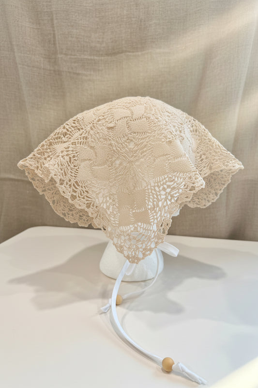 Lace head scarf back view  on a mannequin head against a beige fabric background