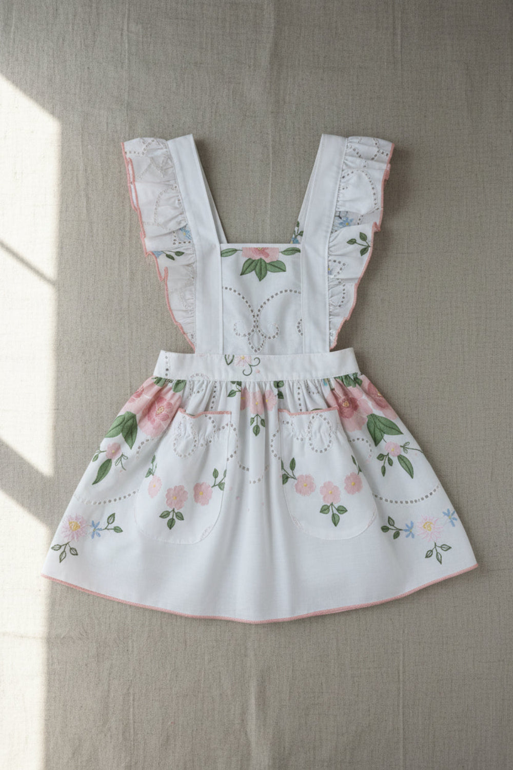 Floral child apron with embroidered details on a neutral background