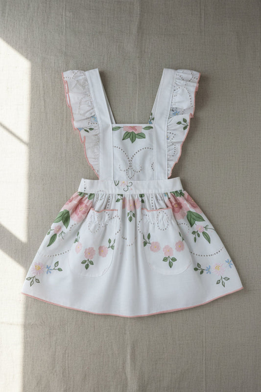 Floral child apron with embroidered details on a neutral background
