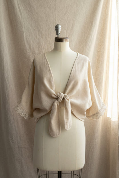 Beige lace shrug on a mannequin against a beige curtain background